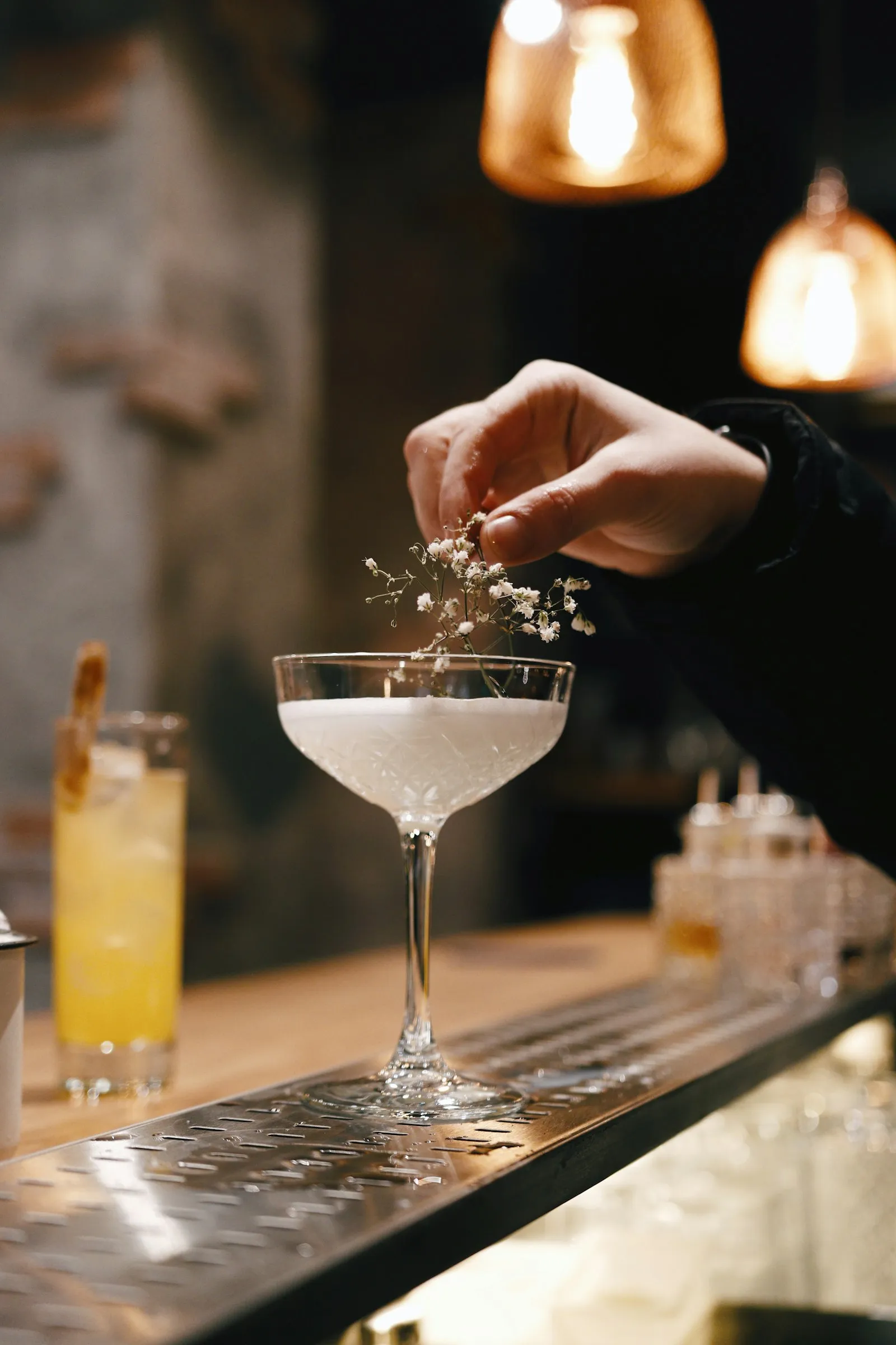 Bartender che decora un cocktail al bancone di un bar